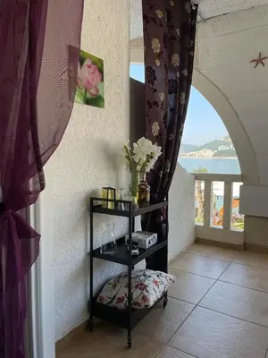 a room with a shelf with flowers and a window at Sea view in Rafailovici