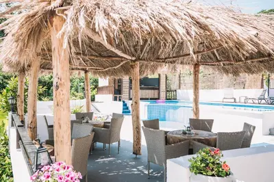 a restaurant with a straw umbrella and a pool at Bivalvia Apartments in Ulcinj