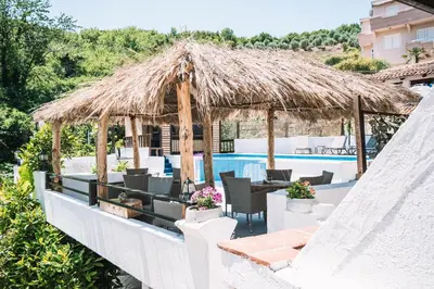a restaurant with a straw umbrella and a swimming pool at Bivalvia Apartments in Ulcinj