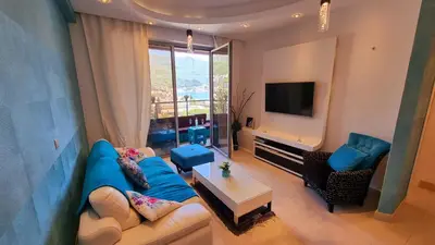 a living room with a blue couch and a tv at Harmonia Budva 1 in Budva