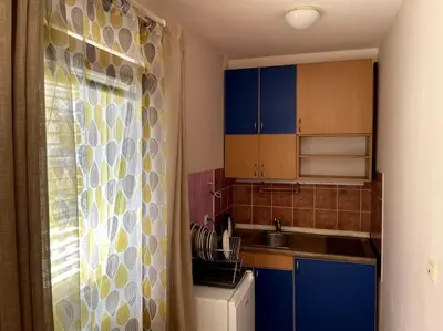 a small kitchen with blue cabinets and a refrigerator at Magnolia Apartment in Budva
