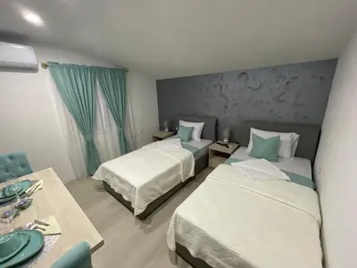 a hotel room with two beds and a table at Apartments Zejak in Mitrovići