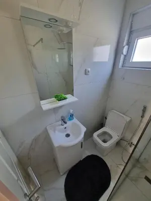 a white bathroom with a sink and a toilet at Apartment Matija Airport in Podgorica