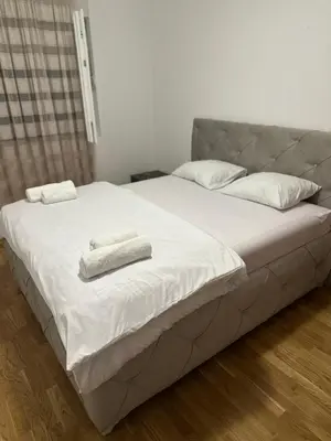 a large white bed with two towels on it at Viktor Apartman in Podgorica