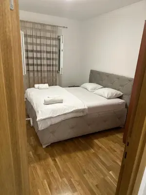 a bedroom with a large bed with white sheets at Viktor Apartman in Podgorica
