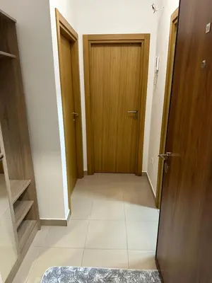 a hallway with a wooden door and a tile floor at Viktor Apartman in Podgorica