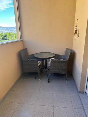 a table and chairs in a room with a window at Viktor Apartman in Podgorica