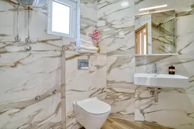 a bathroom with a white toilet and a sink at Ivanovic residences in Budva