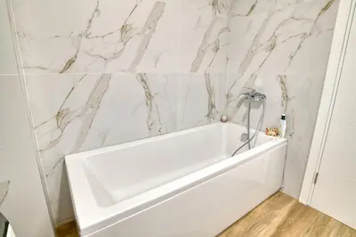 a white bath tub in a bathroom with marble walls at Ivanovic residences in Budva