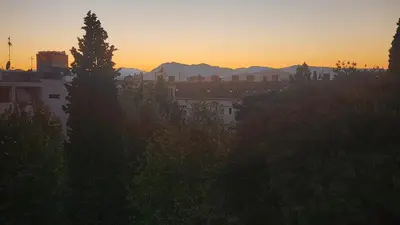 a sunset over a city with buildings and trees at City Center Relax Podgorica in Podgorica
