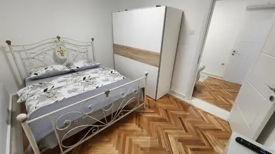 a bedroom with a bed and a wooden floor at City Center Relax Podgorica in Podgorica
