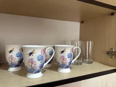 four cups sitting on a shelf in a kitchen at Apartment Simona in Budva