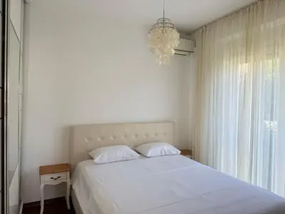 a bedroom with a white bed and a chandelier at Viola Di Mare Apartments in Budva