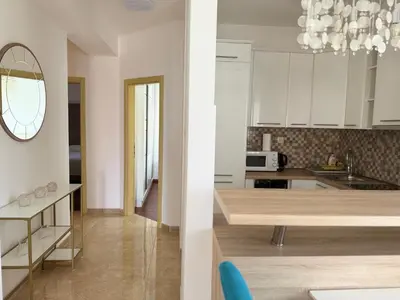 a kitchen with white cabinets and a dining table at Viola Di Mare Apartments in Budva