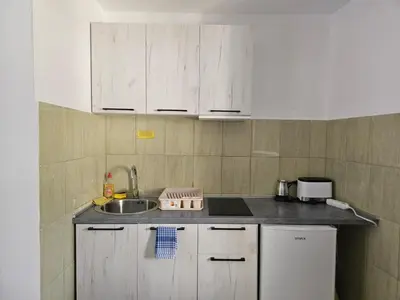 a small kitchen with white cabinets and a sink at Vrsutska 81 in Sutomore