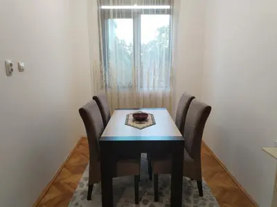 a dining room table with chairs and a window at Vrsutska 81 in Sutomore
