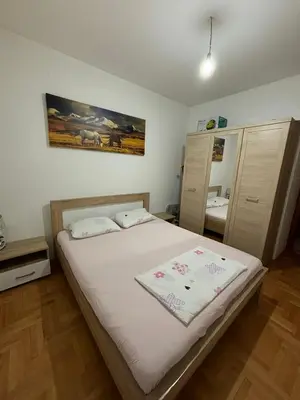a bedroom with a large bed with white sheets at Apartman 38 in Podgorica