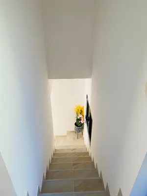 a staircase in a white room with a vase of flowers at Casa Behar in Kotor