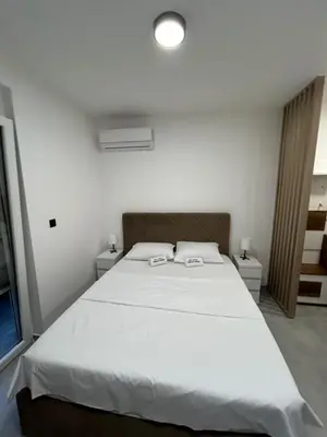a bedroom with a large white bed with two night stands at Apartman Princeza Ksenija in Podgorica