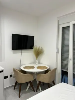 a white table with chairs and a tv on a wall at Apartman Princeza Ksenija in Podgorica