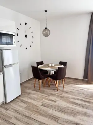 a kitchen with a table and chairs and a clock on the wall at Your Sunny vacation in Budva