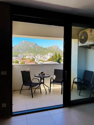 a balcony with a table and chairs and a mountain at MonteСharm in Sutomore