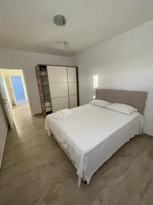 a bedroom with a large white bed and a wooden floor at SeaCharm in Dobra Voda