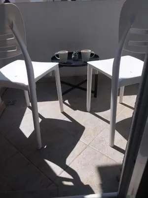 two white chairs and a table with cups on it at NYC Apartman with garage in Podgorica