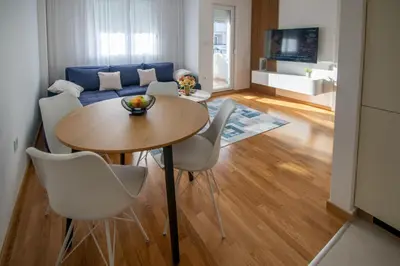 a living room with a table and chairs and a couch at NYC Apartman with garage in Podgorica