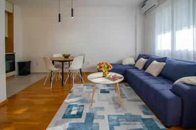a living room with a blue couch and a table at NYC Apartman with garage in Podgorica