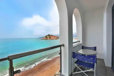 a balcony with a table and a view of the ocean at Plava Vila Beach Apartments Sveti Stefan in Sveti Stefan