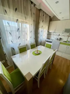 a kitchen with a white table and green chairs at City center 34 in Podgorica