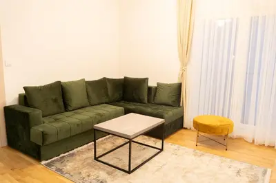 a living room with a green couch and a table at Apartament ZHana in Podgorica