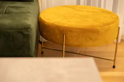 a yellow stool sitting next to a green couch at Apartament ZHana in Podgorica