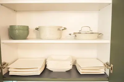 a kitchen with white plates and bowls on shelves at Apartament ZHana in Podgorica