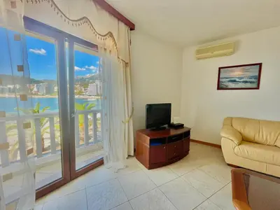 a living room with a television and a large window at Sea view Apartments Rafailovici in Budva