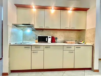 a kitchen with white cabinets and a microwave at Sea view Apartments Rafailovici in Budva