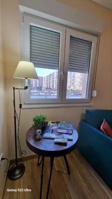a living room with a table and a couch and two windows at Apartment Katarina in Podgorica