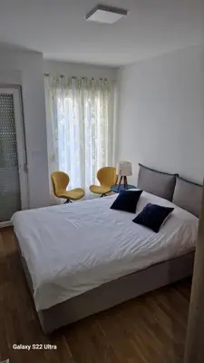 a bedroom with a large bed with two chairs and a window at Apartment Katarina in Podgorica
