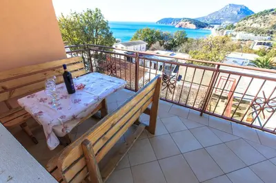 a table with a bottle of wine on a balcony at Apartments Vitic in Sutomore