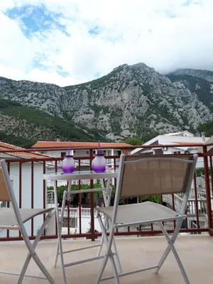 two chairs and a table on a balcony with mountains at Apartments Vitic in Sutomore