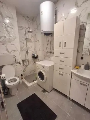 a bathroom with a toilet a sink and a washing machine at DMD Apartman in Podgorica