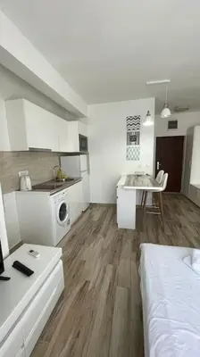 a white kitchen with a bed and a table in a room at Sunny Studio in Bečići in Budva