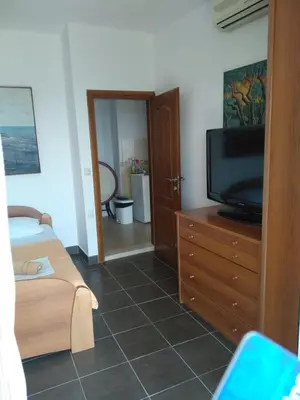 a bedroom with a television on a dresser and a bathroom at Guest House Djakonovic in Ulcinj