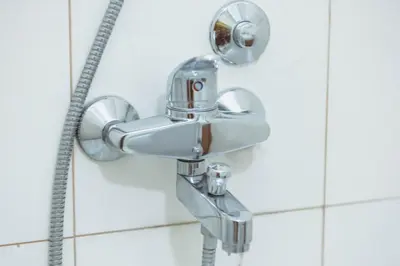 a shower head in a white tiled bathroom at Anika apartment in Podgorica