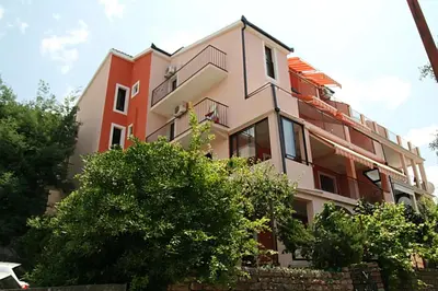 a building with trees in front of it at Apartmani Dalex in Budva