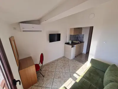 a living room with a green couch and a kitchen at Apartmani Dalex in Budva