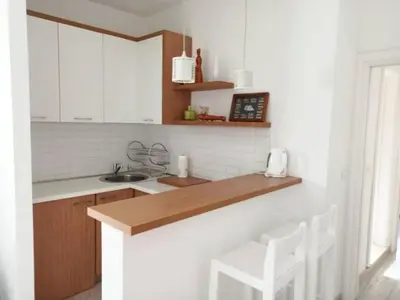 a kitchen with a counter with white cabinets and white chairs at Mediteraneo Apartments in Budva