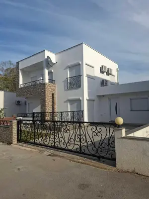 a white building with a black fence in front of it at Dara Apartmani in Donji Štoj