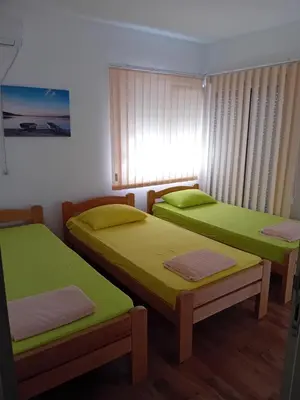 two beds in a room with green sheets at Dara Apartmani in Donji Štoj